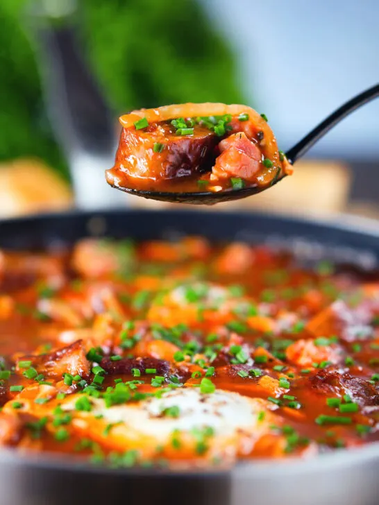 Sausage, bacon, black pudding and baked bean breakfast casserole on a spoon.