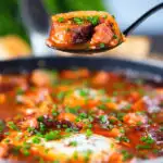 Sausage, bacon, black pudding and baked bean breakfast casserole on a spoon.