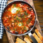 Overhead sausage, bacon, black pudding and baked bean breakfast casserole with toast.