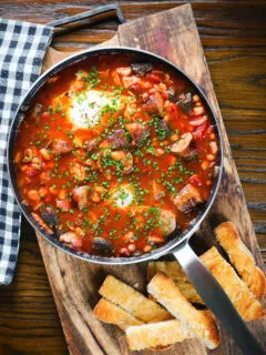 Overhead sausage, bacon, black pudding and baked bean breakfast casserole with toast.