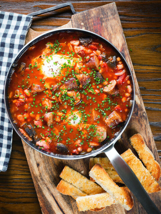 Overhead sausage, bacon, black pudding and baked bean breakfast casserole with toast.