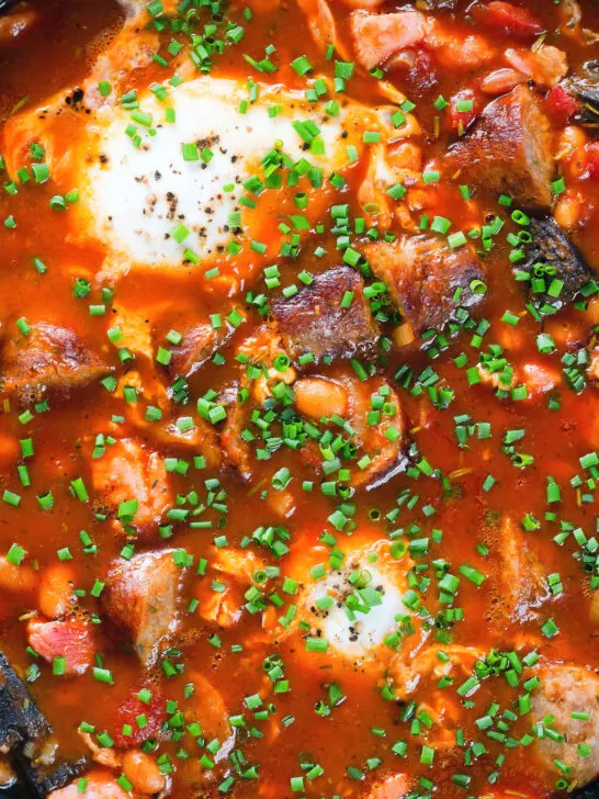 Overhead close-up sausage, bacon, black pudding and baked bean breakfast casserole.