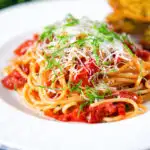 Spaghetti Napolitana or pasta pomodoro (tomato) garnished with basil and pecorino cheese.