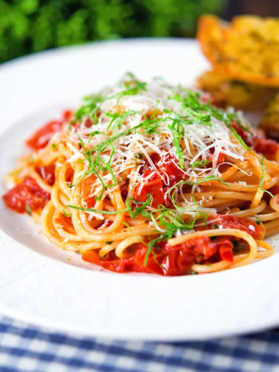Spaghetti Napolitana or pasta pomodoro (tomato) garnished with basil and pecorino cheese.
