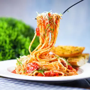 Spaghetti Napolitana or pasta pomodoro garnish with basil and pecorino cheese.