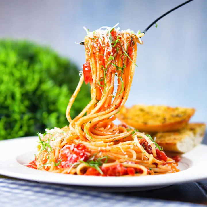 Spaghetti Napolitana or pasta pomodoro garnish with basil and pecorino cheese.