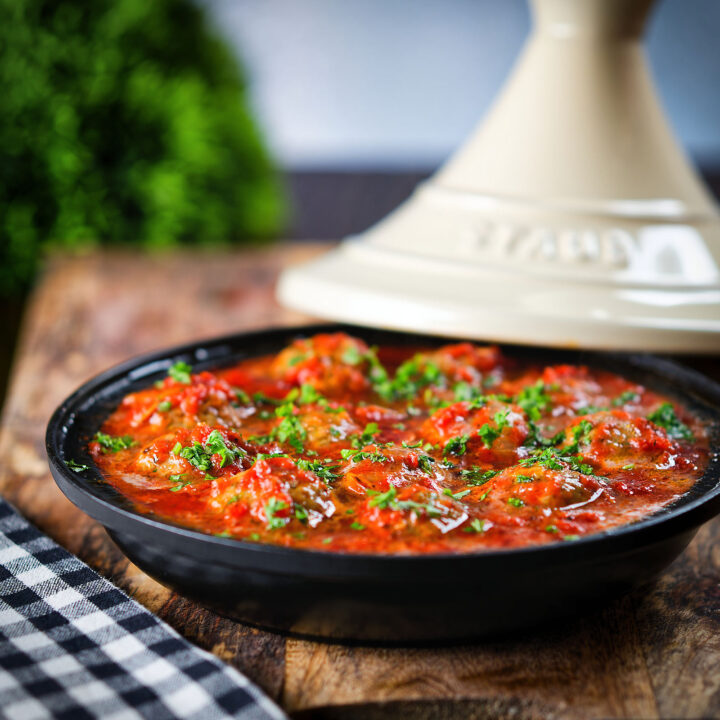Spicy Moroccan-influenced lamb meatball tagine garnished with chopped parsley.