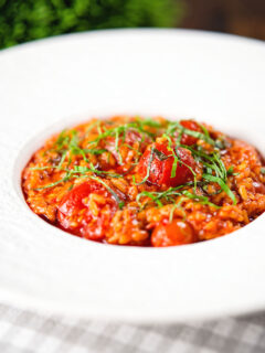 Spicy nduja sausage and cherry tomato risotto garnished with basil.