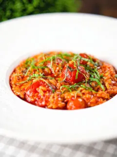 Spicy nduja sausage and cherry tomato risotto garnished with basil.