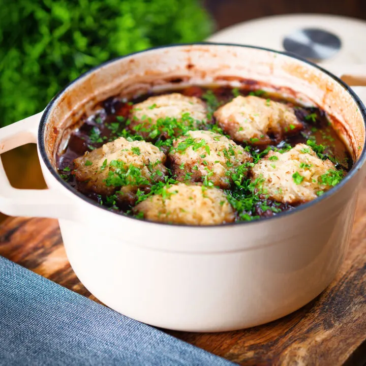 Red wine venison stew or casserole in a Dutch oven with suet dumplings.