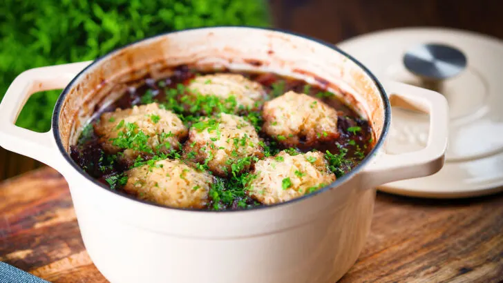 Red wine venison stew or casserole in a Dutch oven with suet dumplings.