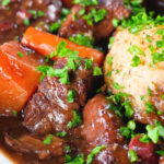 Close-up rich red wine and port venison stew or casserole with suet dumplings.