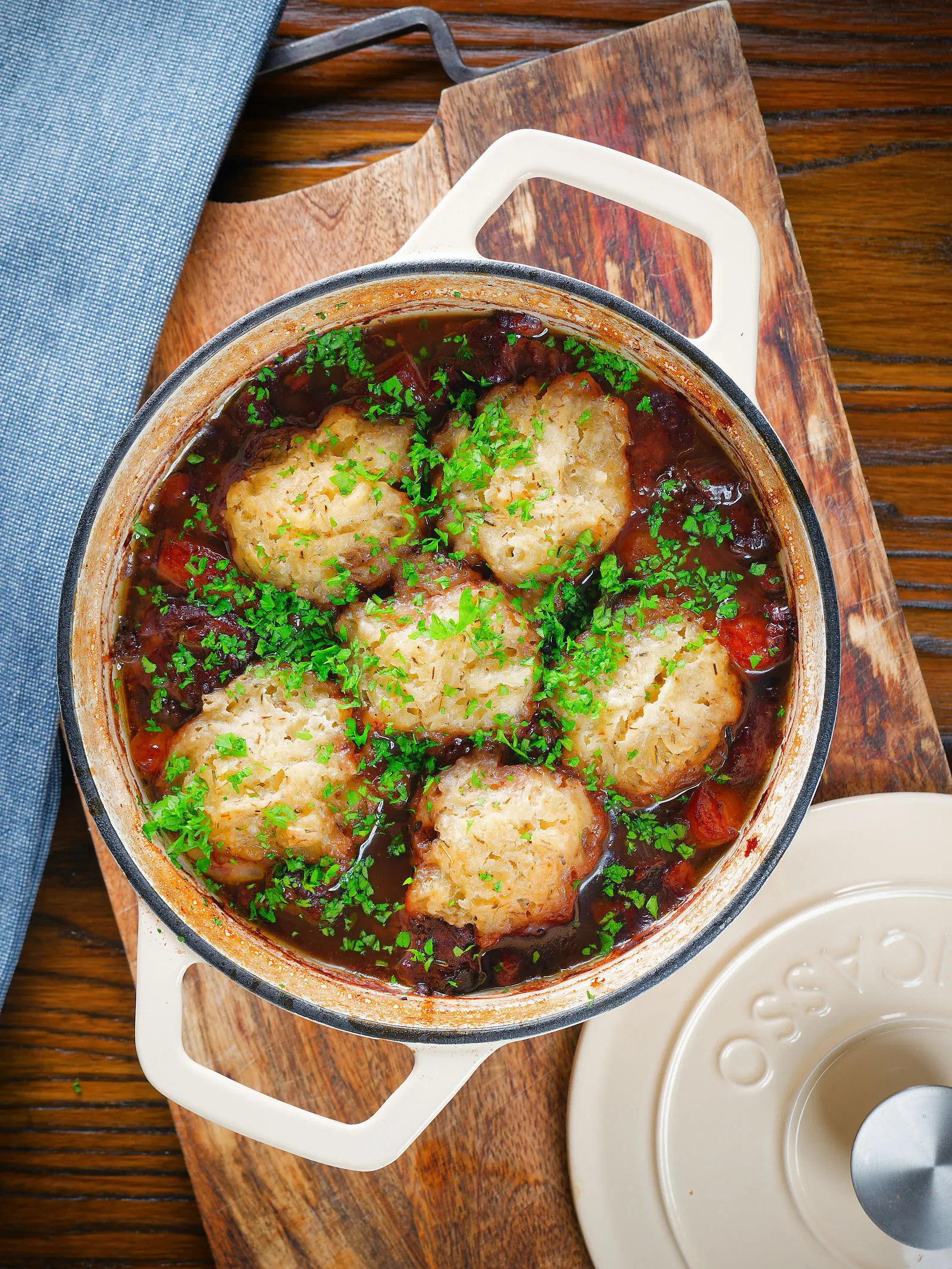 Overhead red wine and port venison stew or casserole with suet dumplings in a Dutch oven.