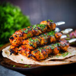 Chicken tikka kebab skewers garnished with coriander, served with chapati flatbreads.