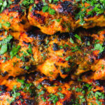 Close-up chicken tikka kebab skewers garnished with fresh coriander.