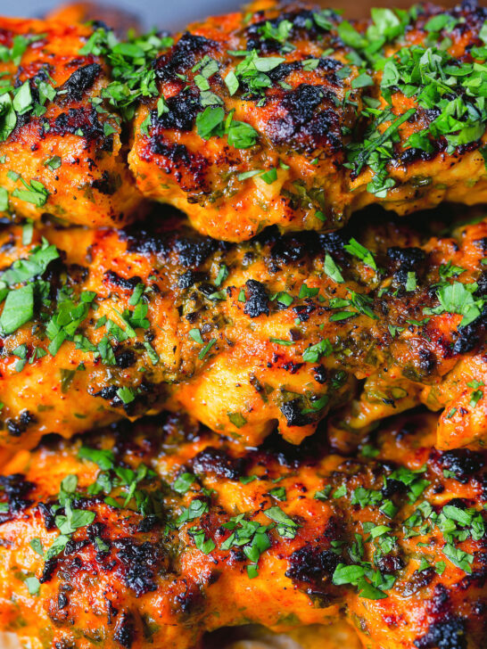 Close-up chicken tikka kebab skewers garnished with fresh coriander.