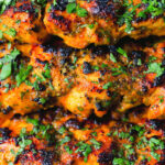 Close-up chicken tikka kebab skewers garnished with fresh coriander.