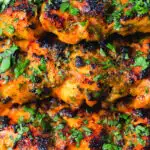Close-up chicken tikka kebab skewers garnished with fresh coriander.
