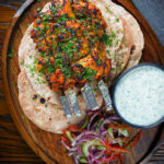 Overhead chicken tikka kebab skewers served with chapati, raita and kachumber salad.