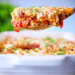 Corned beef and tomato macaroni pasta bake being served with a spoon.