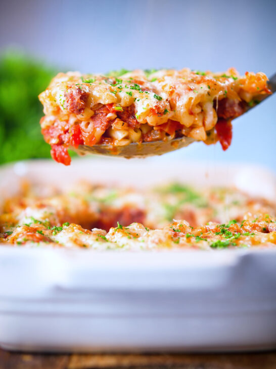 Corned beef and tomato macaroni pasta bake being served with a spoon.