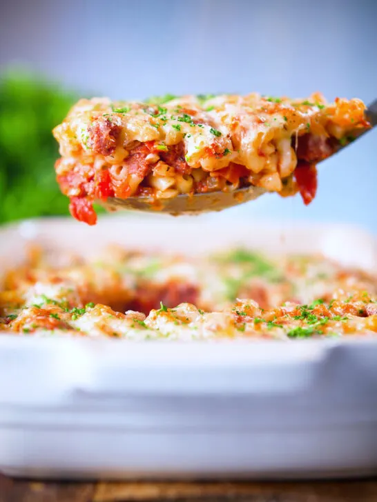 Corned beef and tomato macaroni pasta bake being served with a spoon.