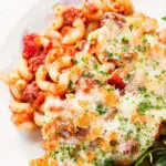 Overhead corned beef and tomato macaroni pasta bake served with a side salad.
