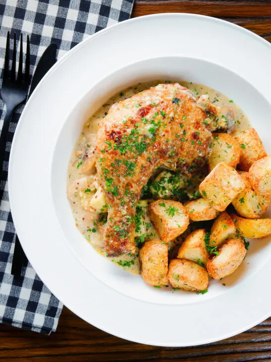 Overhead Somerset chicken legs in a creamy cider and cheddar sauce served with mini roast potatoes.