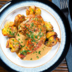 Overhead Dijon chicken leg or poulet Gaston Gerard served with roasted crushed new potatoes.