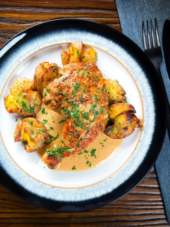 Overhead Dijon chicken leg or poulet Gaston Gerard served with roasted crushed new potatoes.