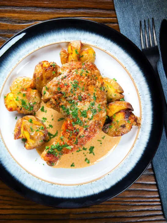 Overhead Dijon chicken leg or poulet Gaston Gerard served with roasted crushed new potatoes.