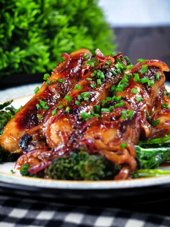 Close-up honey and mustard glazed sausages with mashed potato and tenderstem broccoli.