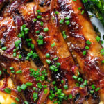 Close-up overhead honey and mustard glazed sausages with mashed potato and tenderstem broccoli.
