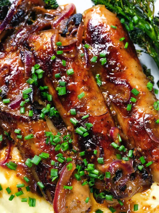 Close-up overhead honey and mustard glazed sausages with mashed potato and tenderstem broccoli.