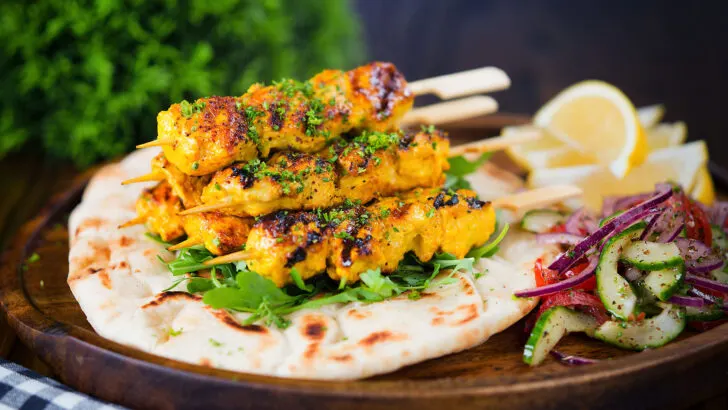 Persian joojeh kabob (saffron chicken) served with rocket and flatbreads.