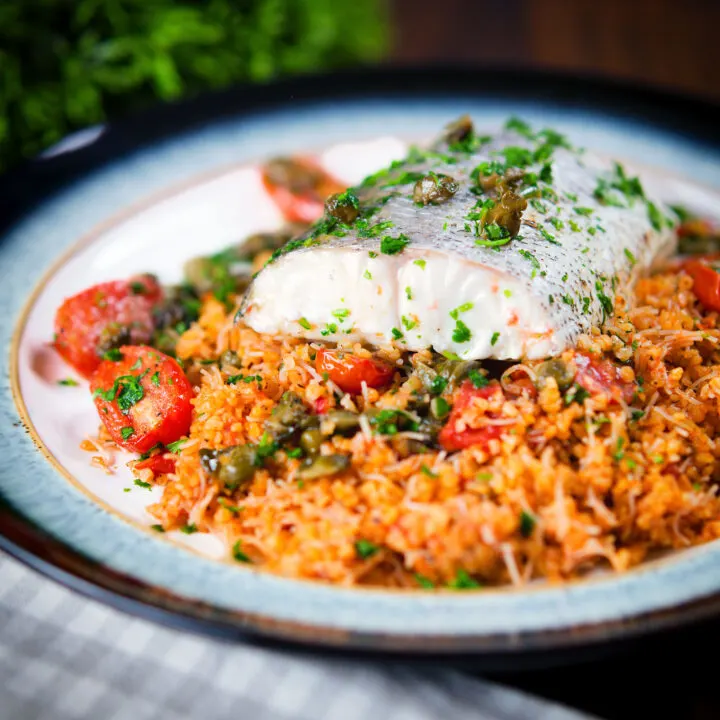 Roasted hake fillet with cherry tomatoes and capers served with pourgouri.