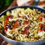 Sausage and lentil stew with cabbage, apples and English mustard served in its cooking pot.