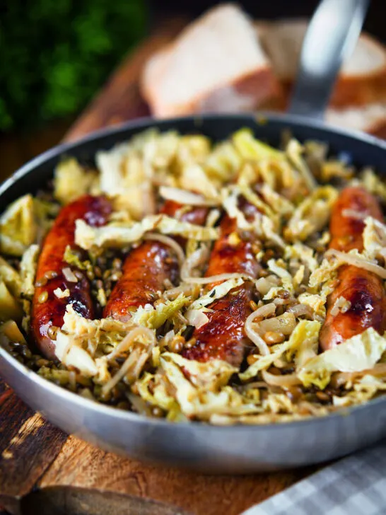 Sausage and lentil stew with cabbage, apples and English mustard served in its cooking pot.