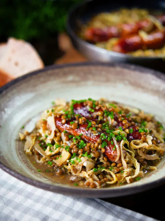 Sausage and lentil stew with cabbage, apples and English mustard served with bread.