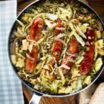 Overhead sausage and lentil stew with cabbage, apples and English mustard served in its cooking pot.
