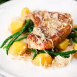 Slow cooker pork chops and sauerkraut with potatoes and green beans.