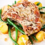Close-up slow cooker pork chops and sauerkraut with potatoes and green beans.