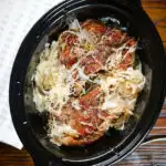 Overhead slow cooker pork chops and sauerkraut with potatoes.