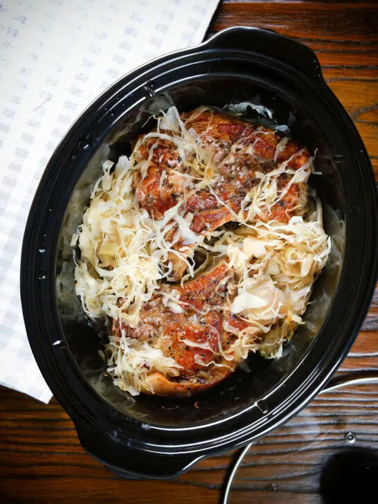 Overhead slow cooker pork chops and sauerkraut with potatoes.
