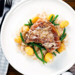 Overhead slow cooker (crock pot) pork chops and sauerkraut with potatoes and green beans.