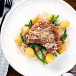 Overhead slow cooker (crock pot) pork chops and sauerkraut with potatoes and green beans.