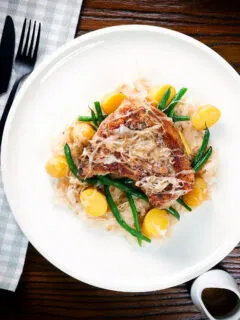 Overhead slow cooker (crock pot) pork chops and sauerkraut with potatoes and green beans.