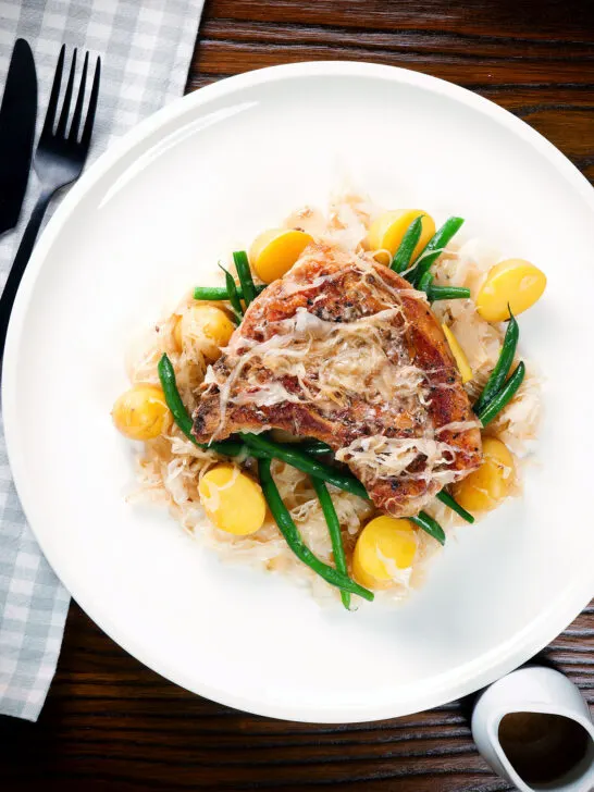 Overhead slow cooker (crock pot) pork chops and sauerkraut with potatoes and green beans.