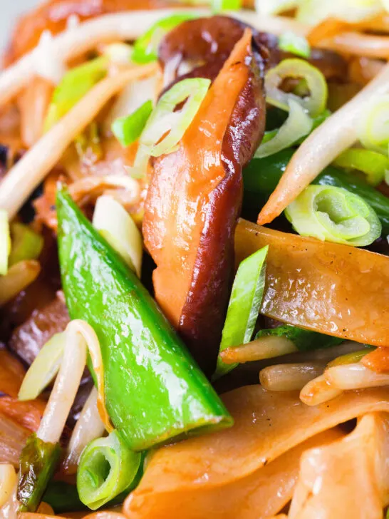 Close-up ho fun noodles stir fry with bean sprouts, shiitake mushrooms and sugar snap peas.