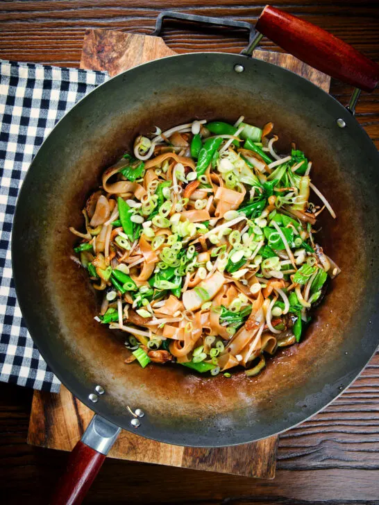 Overhead vegetarian ho fun (ho fan) noodles stir fry in a wok.